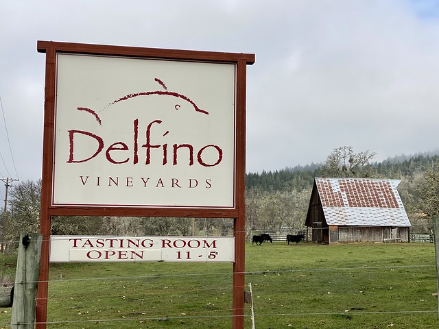 Delfino Vineyards Tasting Room sign with cows and barn in the background in Roseburg, Oregon.