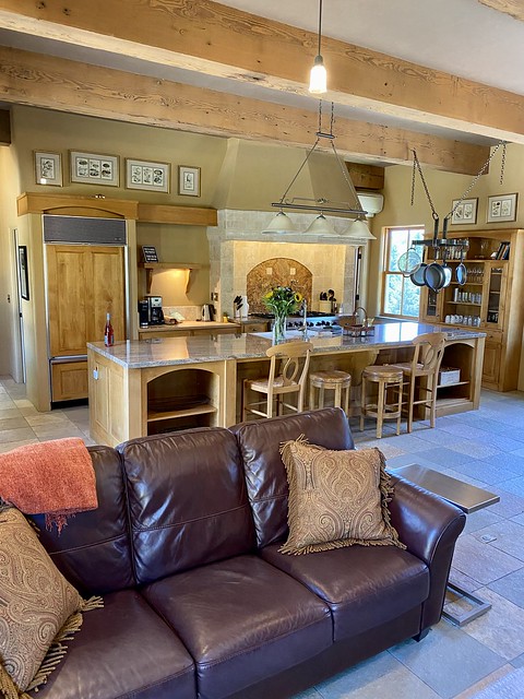 Brown leather sofa with pillows opens to gourmet kitchen at Iris Vineyards guest house in Willamette Valley wine country. 