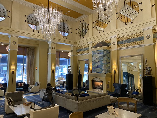 Kimpton Hotel Monaco Seattle lobby with yellow and blue colors. Two delicate crystal chandeliers hang from the high ceiling.