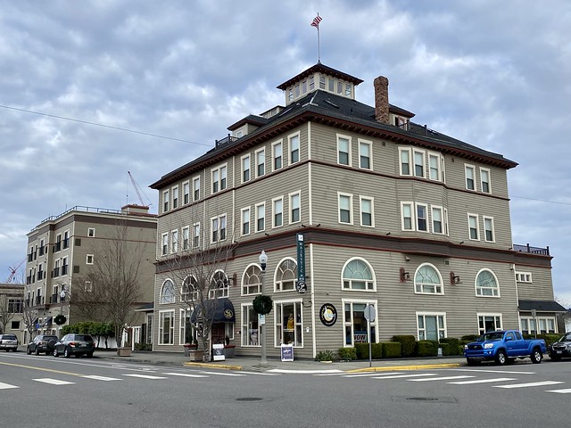 Exterior photo, street view of Majestic Inn & Spa on Commercial Avenue in downtown Anacortes, Washington. Five-story historic boutique hotel with beige siding and rectangular windows on every level. 
