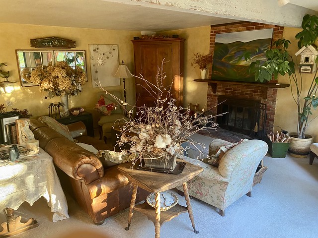 Tuscan Country Home living room with antique furniture, leather sofa, dried flower arrangements and countryside landscape painting above the fireplace. 
